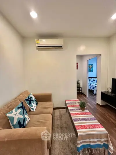 Cozy living room with modern decor and air conditioning, leading to a stylish bedroom.