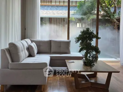 Elegant living room with modern sofa and large window overlooking serene garden view.