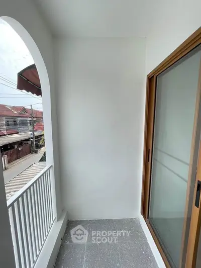 Charming small balcony with sliding glass door and street view, perfect for relaxation.
