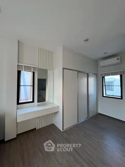 Modern bedroom with built-in wardrobe and air conditioning, featuring sleek design and natural light.