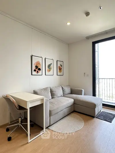 Modern living room with cozy sofa, desk, and balcony access in stylish apartment.
