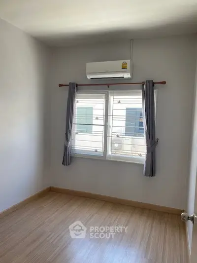 Bright empty room with wooden flooring and air conditioning, perfect for customization.