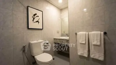 Modern bathroom with elegant tile design and framed artwork, featuring a sleek toilet and vanity area.