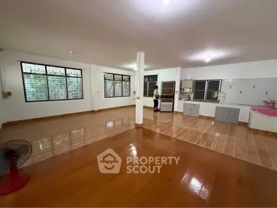 Spacious open-plan living and kitchen area with large windows and polished wooden floors.