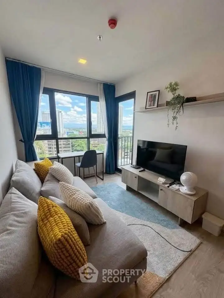 Modern living room with cozy sofa, large windows, and city view, perfect for relaxation and entertainment.