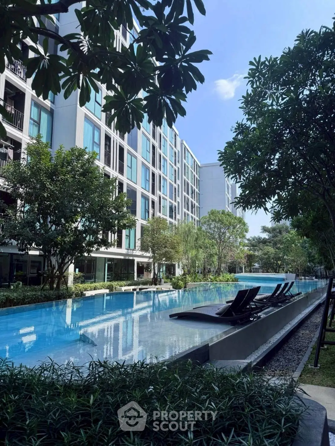 Luxurious apartment complex with serene pool and lush greenery