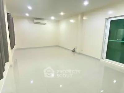 Spacious empty room with glossy tiled floor and air conditioning unit.