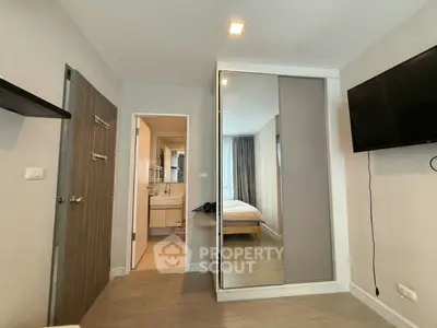 Modern bedroom with mirrored wardrobe and wall-mounted TV in a stylish apartment.