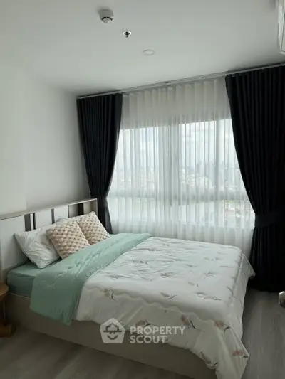 Cozy bedroom with large window and elegant curtains, offering a serene city view.