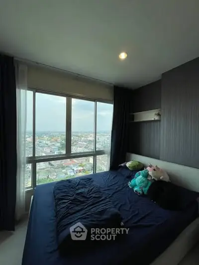Cozy bedroom with large window offering stunning city views, perfect for relaxation and comfort.