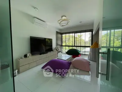 Modern living room with large windows and colorful bean bags