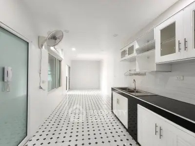 Spacious modern kitchen with sleek black countertops and white cabinetry, featuring elegant tile flooring.