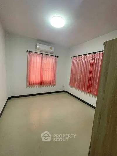 Spacious empty room with pink curtains and air conditioning, perfect for customization.
