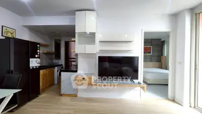 Modern open-plan living room with sleek kitchen and cozy bedroom view.