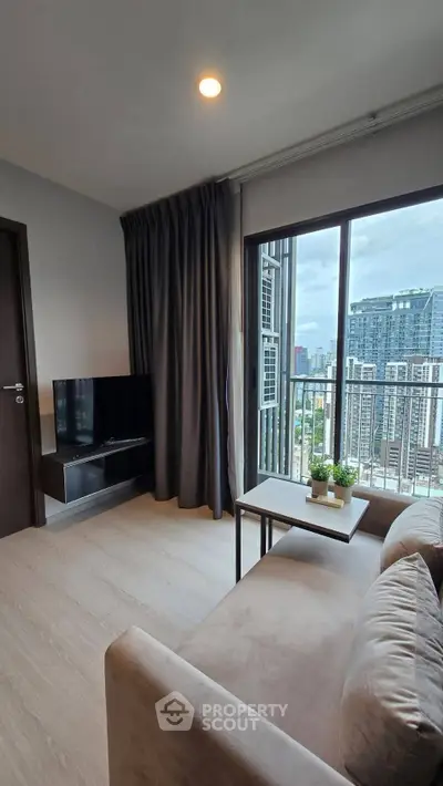 Modern living room with city view, cozy sofa, and sleek TV setup in a high-rise apartment.