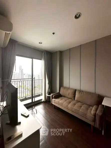 Modern living room with city view, featuring a cozy sofa and sleek TV setup.