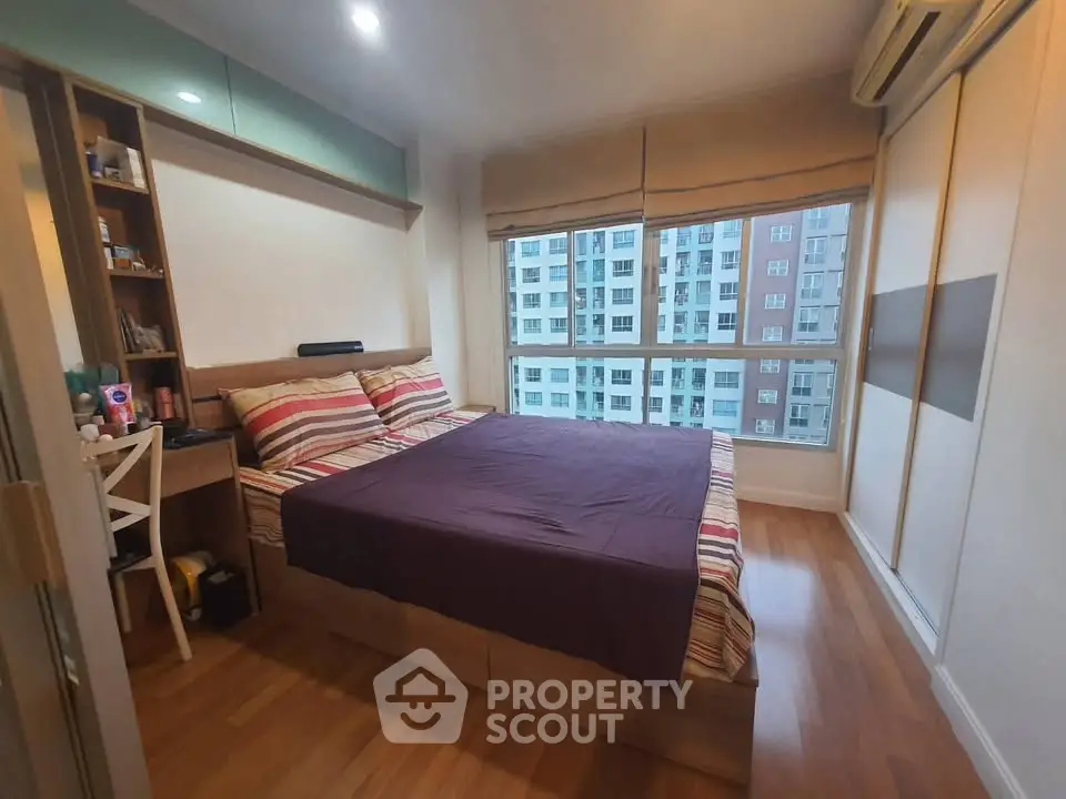 Cozy bedroom with large window and city view, featuring modern decor and ample storage space.