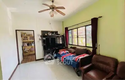 Cozy living room with ceiling fan, large window, and comfortable seating in a bright home.