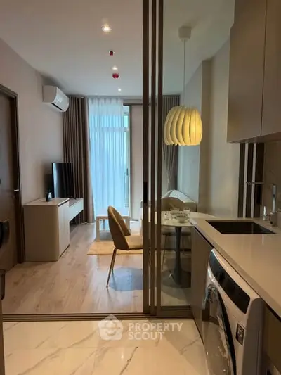 Modern apartment interior with open kitchen and living area, featuring stylish lighting and washing machine.