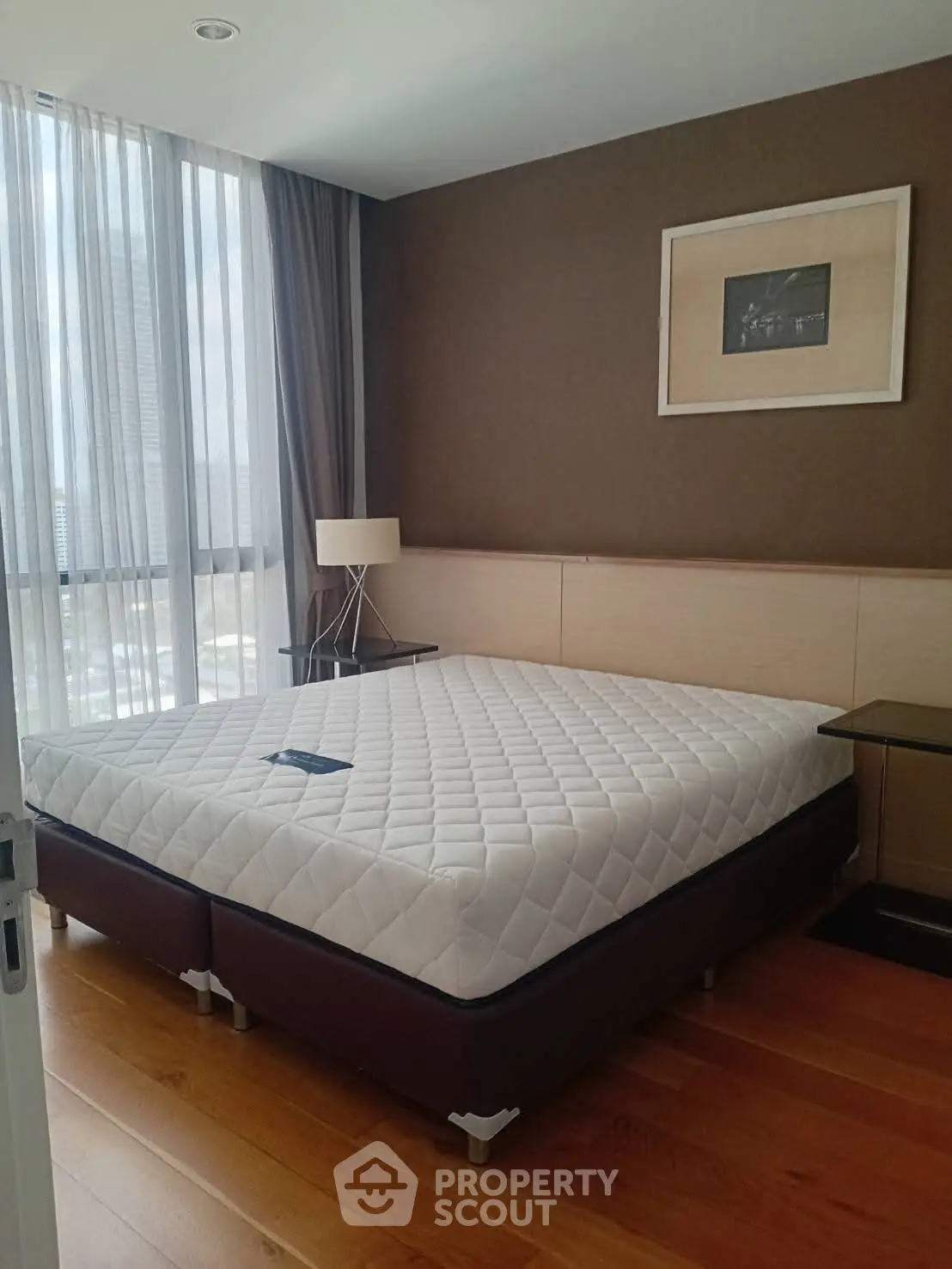 Modern bedroom with large window and stylish decor in a high-rise apartment.