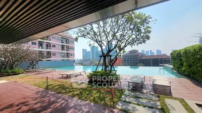 Luxurious rooftop pool with stunning city skyline view and lush greenery.