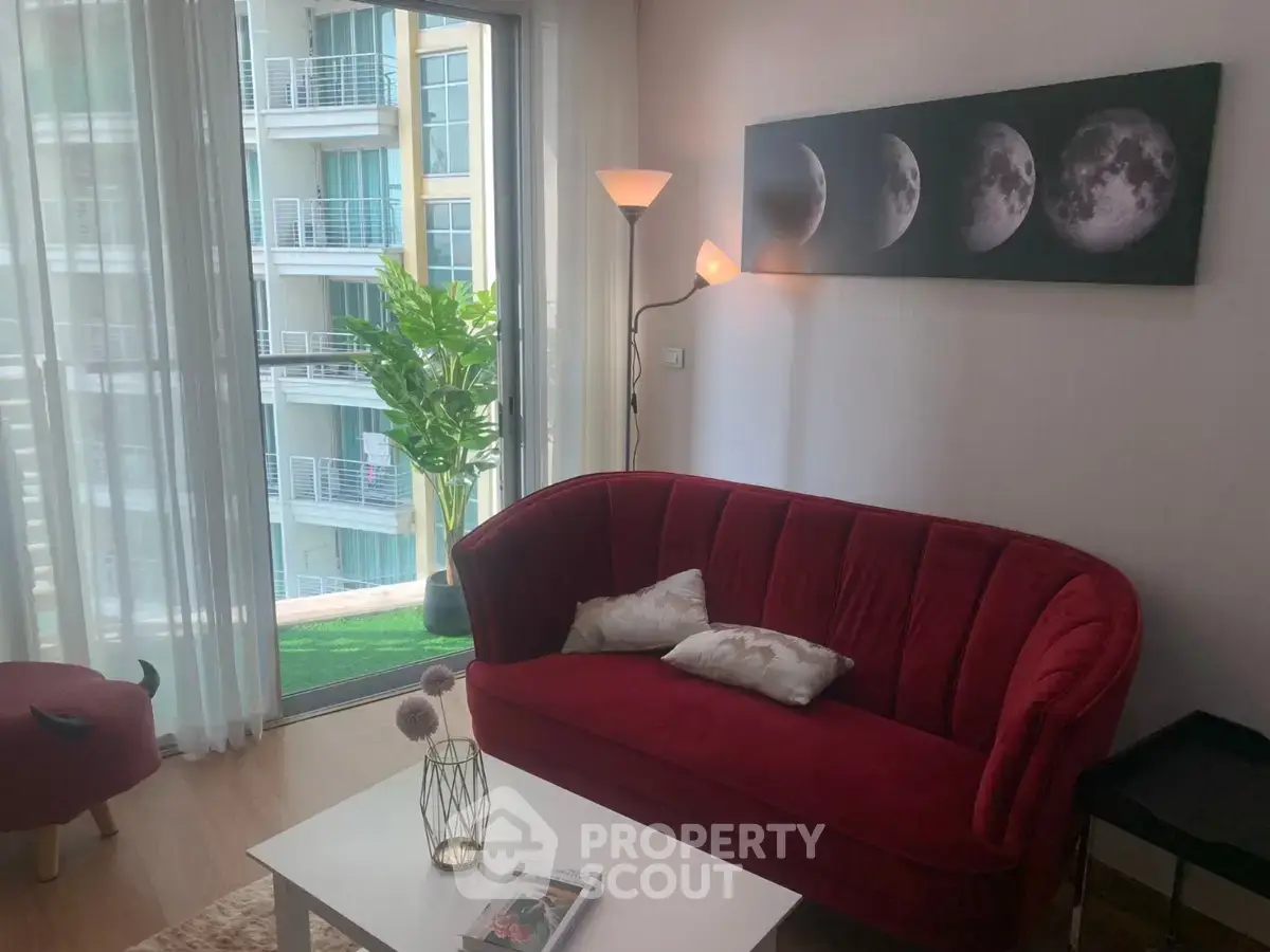 Chic living room with red velvet sofa and moon phase artwork, overlooking modern balcony view.