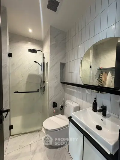 Modern bathroom with glass shower, sleek sink, and stylish tiles