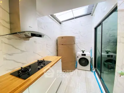 Modern kitchen with gas stove and laundry area in bright natural light