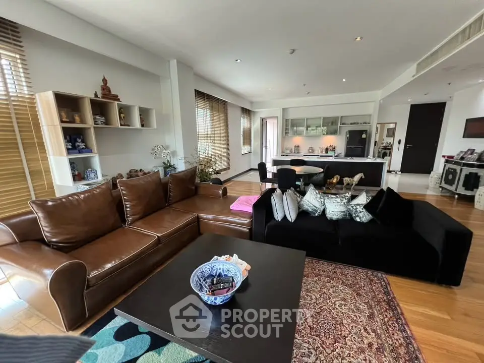 Spacious living room with modern decor and open kitchen layout, featuring elegant furniture and natural light.