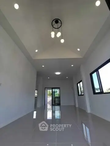Spacious modern living room with high ceiling and elegant lighting in a contemporary home.