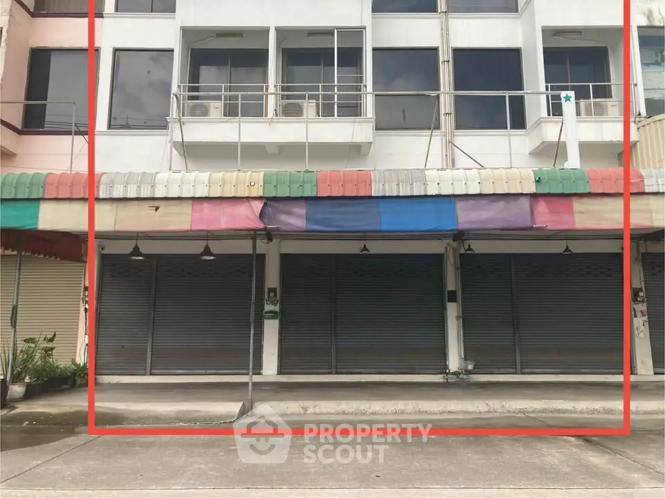 Commercial building with closed shutters and colorful awning, ideal for retail or office space.