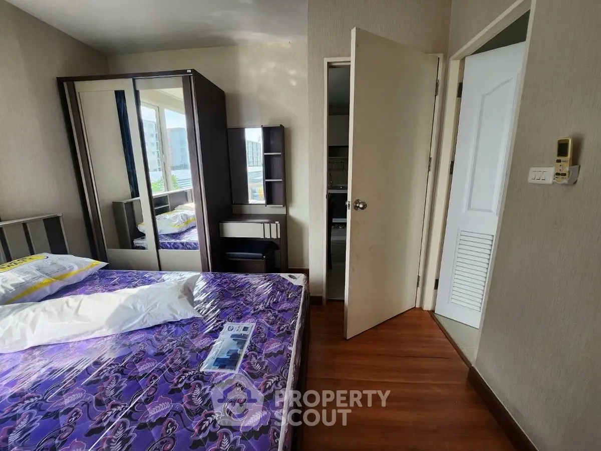 Cozy bedroom with mirrored wardrobe and wooden flooring in modern apartment.