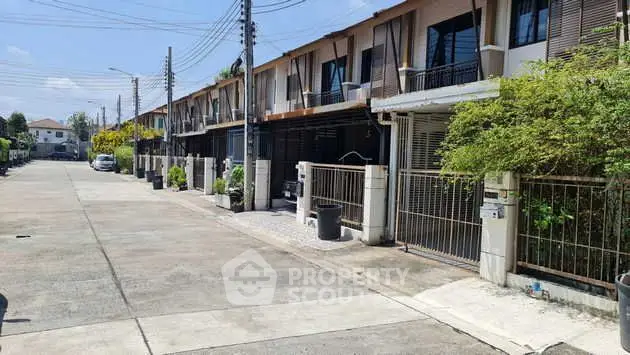 Charming row of modern townhouses with gated entrances and lush greenery in a serene neighborhood.