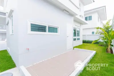 Modern white house exterior with lush green lawn and tiled patio