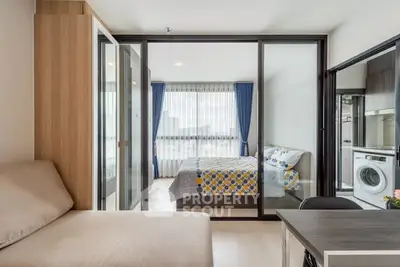 Modern apartment with cozy living area and bedroom, featuring a washing machine and stylish decor.