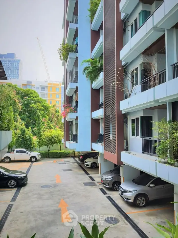 Modern apartment building with parking area and lush greenery.