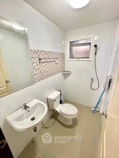 Modern bathroom with sleek fixtures and tiled walls, featuring a shower and compact design.