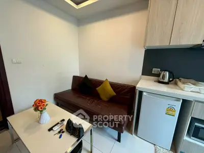 Cozy living area with compact kitchenette, featuring a leather sofa and modern appliances.
