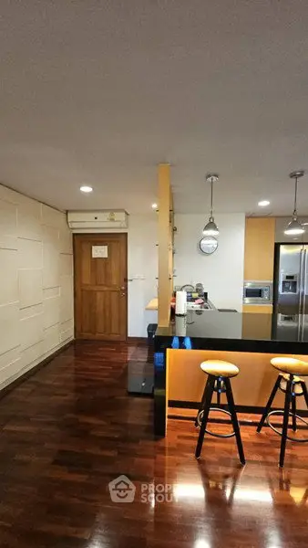 Modern kitchen with sleek design, featuring a breakfast bar and wooden flooring.