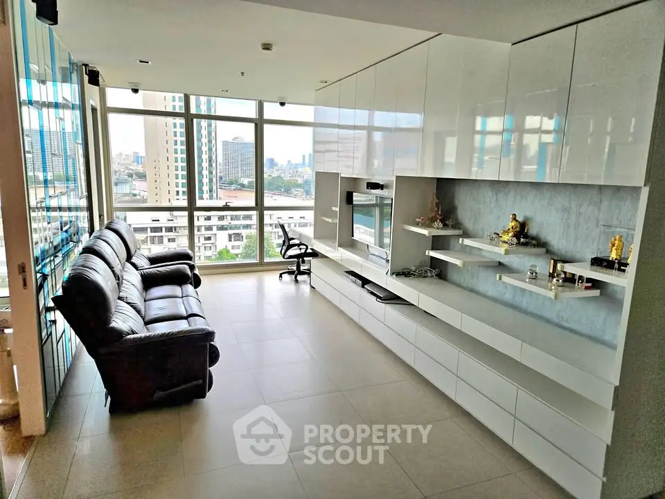 Spacious modern living room with city view, sleek white cabinetry, and comfortable seating.