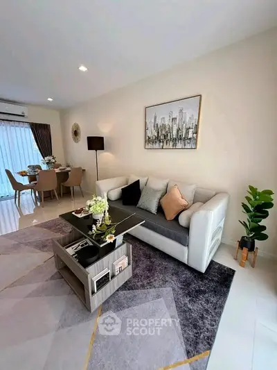 Modern living room with stylish decor and dining area, featuring elegant furniture and contemporary artwork.