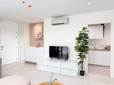 Modern living room with sleek white furniture and open kitchen layout