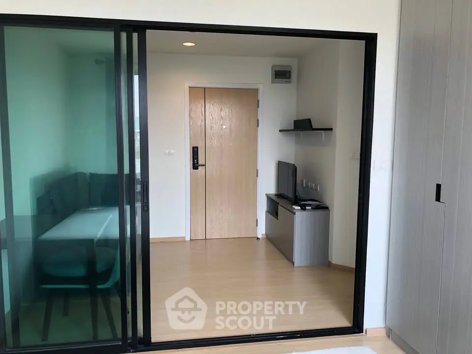 Modern apartment interior with sliding glass doors and sleek wooden flooring.