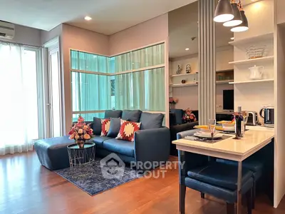 Stylish modern living room with open kitchen, featuring elegant decor and cozy seating area.