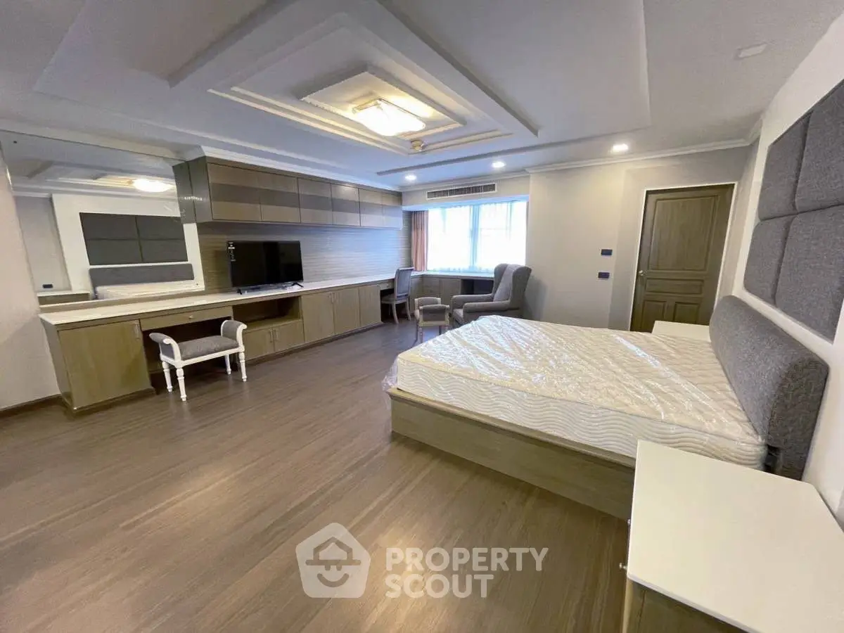 Spacious modern bedroom with elegant wooden flooring and stylish ceiling design.