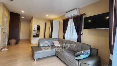 Spacious living room with modern sofa and wall-mounted TV in a cozy apartment.
