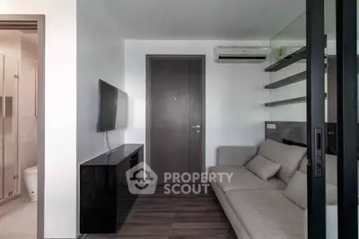 Modern living room with sleek design, wall-mounted TV, and cozy sofa in a compact space.