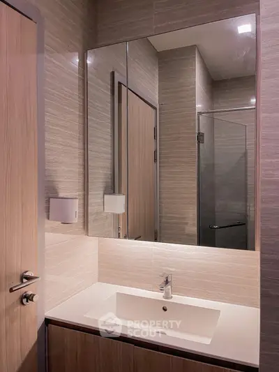 Modern bathroom with sleek sink and large mirror in contemporary design.