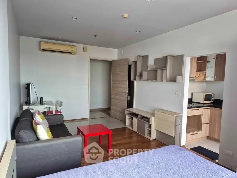 Modern studio apartment with open layout, featuring cozy living area and compact kitchen.