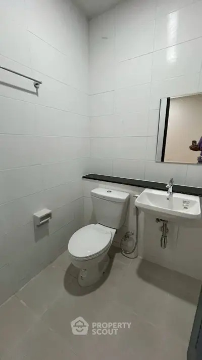 Modern minimalist bathroom with white tiles and sleek fixtures.